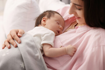Mother with her sleeping newborn baby in bed