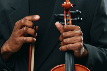 Close up portrait of man in suit playing violin with bow in hand, music and art concept