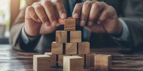 Crafting Essence: Hands Strategically Arrange Wooden Blocks, Forming a Meaningful Structure that Embodies Business Concept and Development Strategy.