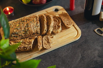 Healthy multi grain cut bread with seeds on a wooden board is standing on festive table