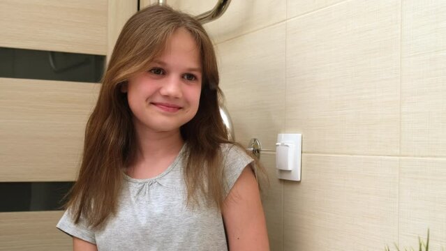 Portrait happy cute young preteen girl in bathroom.Children daily healthcare routine. Caucasian smiling little girl looking at her mirror reflection at home