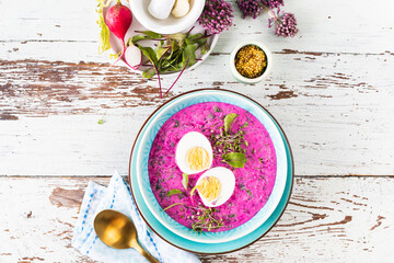 Cold soup made from beets, cucumbers and garnished with an egg in wooden background.