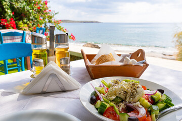 Typical Greek dishes served on a Greek tavern table with the Aegean Sea in the background and...