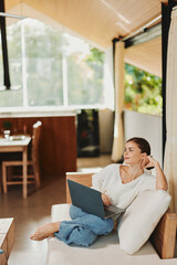 Happy Woman Working on Laptop in Modern Home Office, Surrounded by Technology and Lifestyle Essentials