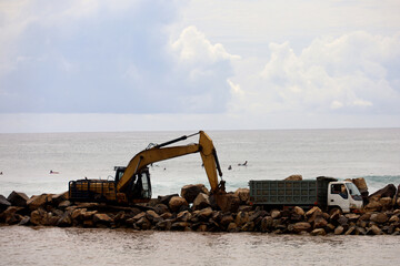 Fototapeta premium Trucks and excavators are working to unload material for a reclamation project on the coast of Bali, Indonesia. the process of making embankments on the beach to anticipate abrasion.