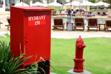 fire extinguisher box and hydrant in outdoor grass garden. red hydrant beside the swimming pool. - Powered by Adobe