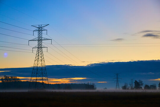 Sunrise Over Foggy Fields with Electricity Pylons in Rural Michigan