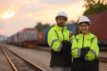 Male and Female engineers with geen safety jackets working at train station
