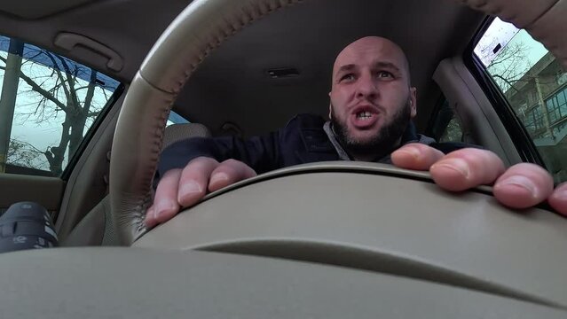 Angry driver drinking coffee and aggressive screaming at someone in car in traffic jam