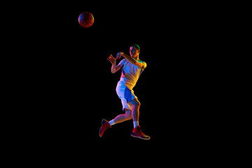 Fototapeta na wymiar Body size photo of young athlete man doing powerful pass in action against black studio background in mixed neon light. Concept of professional sport, energy, strength and power, match, tournament.