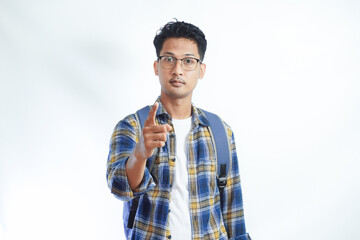 Angry young Asian man student in casual clothes backpack glasses standing pointing finger on camera isolated on white background. high school university college concept