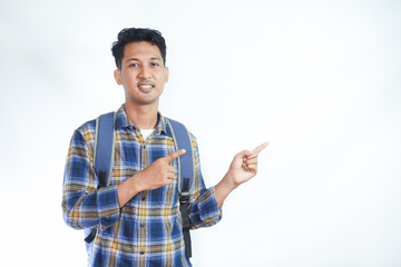 Cheerful Asian male student wearing casual clothes and backpack glasses pointing finger and palm at empty space isolated on white background. high school university college concept