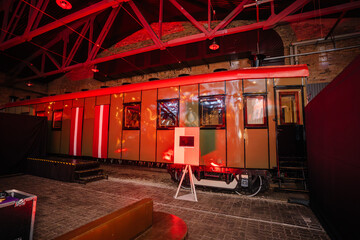 Riga, Latvia - February 16, 2024 - a vintage train car inside a venue with red ambient lighting and...