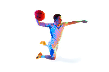 Focused basketball player in game progress doing powerful dunk in motion against white studio background in neon light. Concept of professional sport, energy, strength and power, match, tournament.