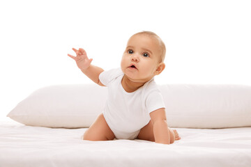 Little baby child, girl, infant crawling on bed with pillow, looking upwards with attention and...