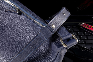 Part of a blue leather bag on a black background. Leather goods.