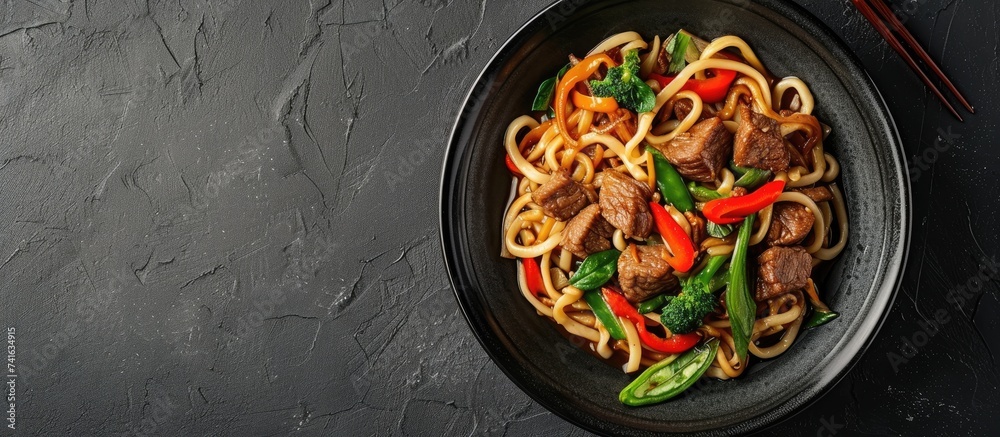 Poster Chinese udon noodles with stir fried veal and vegetables served on plate. with copy space image. Place for adding text or design