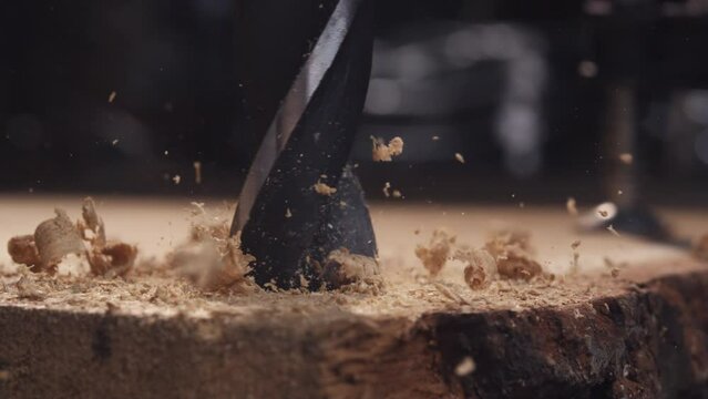 Experience the captivating sight of a drill cutting through wood in slow motion, highlighting the craftsmanship of woodworking