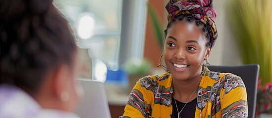 A young Black woman greets a client sitting at her office desk. with copy space image. Place for adding text or design - Powered by Adobe