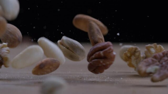 Variety of Nuts Tumbling Down Slowly &ndash; Close-up of Almonds, Walnuts, Pecans, Cashews, Hazelnuts, and Pistachios on Surface