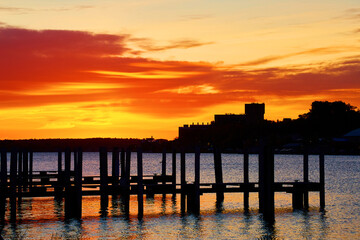 Vibrant Sunset Reflections on Calm Water with Pier Silhouette