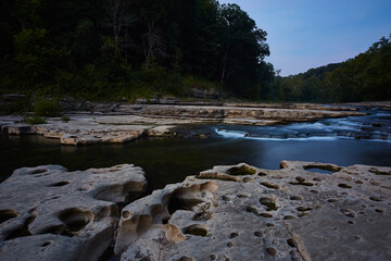 Serene Waterfall at Blue Hour, Rocky Riverbed and Forest View