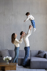 Family, father lifting child on sofa at home. Dad playing flying plane in air game with son on...