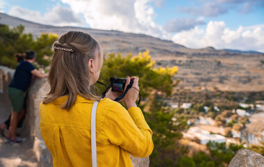 A woman photographer takes pictures of the Lindos beach.