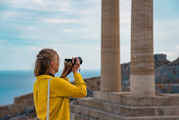 A woman tourist with a camera in the Acropolis on an excursion.