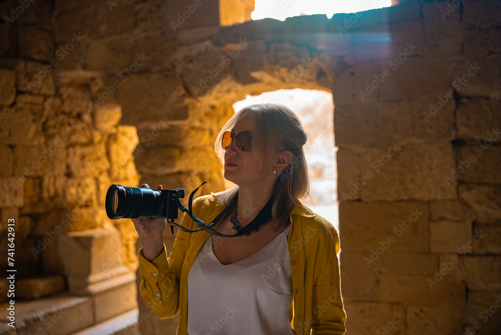 Wall mural A woman tourist with a camera inside an ancient temple.