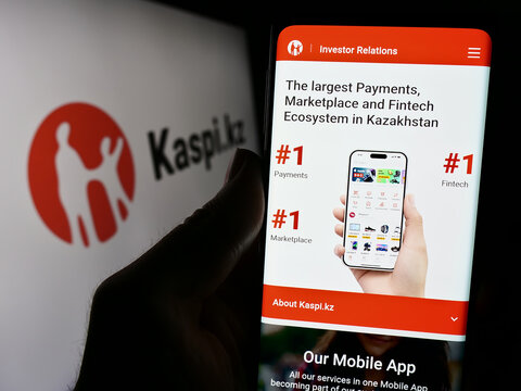 Stuttgart, Germany - 02-13-2024: Person holding cellphone with website of Kazakh financial services company Kaspi.kz in front of business logo. Focus on center of phone display.