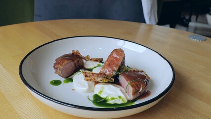 Meat with sour cream on a white plate. Juicy steak with yogurt. Close-up of a tasty meat dish. Juicy roast beef steak. Professional gourmet cuisine.