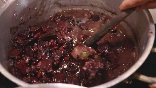 hands stirring pan with brazilian feijoada