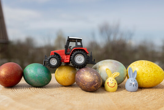 model of a toy red tractor stands on colorful Easter eggs. Business concept for Easter greetings for farms. postcard. copy space