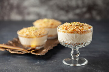 Traditional milky crispy Ramadan dessert custard pudding with roasted kadayif and diced pistachio . Kadayifli Muhallebi