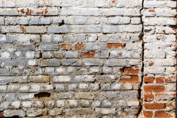 A bare broken ruined brick wall with cracks