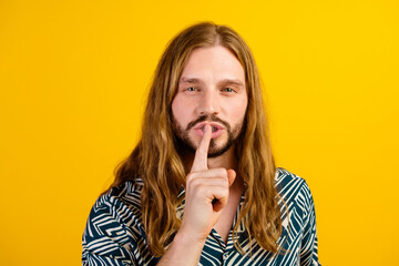 Photo of cheerful funny guy wear print shirt finger lips asking keep silence isolated yellow color background