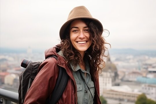 Portrait of a smiling young woman with backpack and hat looking at camera