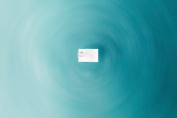 Aerial view of a white wooden platform floating in the middle of the ocean, with a radial blur effect applied to the water, Port Elliot, South Australia, Australia.