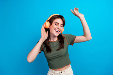 Photo of pretty overjoyed lady closed eyes arm touch headphones dance isolated on blue color...