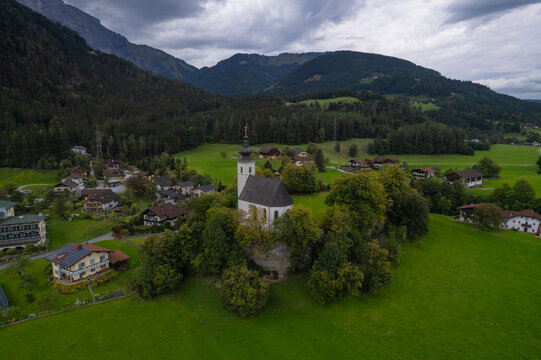 Aerial drone view of Wallfahrtskirche St. Nikolaus with Golling an der Salzach in background at cloudy day, Golling an der Salzach, Salzburg, Austria.