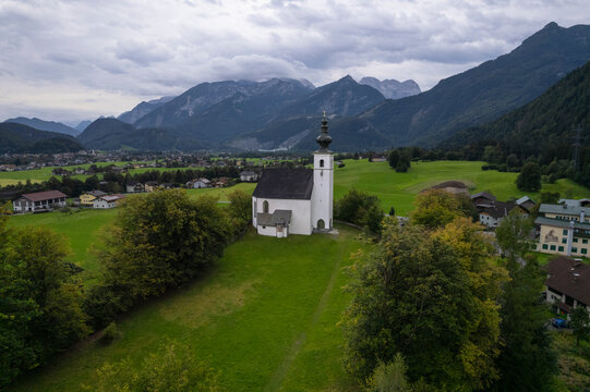 Aerial drone view of Wallfahrtskirche St. Nikolaus with Golling an der Salzach in background at cloudy day, Golling an der Salzach, Salzburg, Austria.