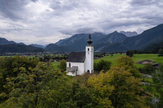 Aerial drone view of Wallfahrtskirche St. Nikolaus with Golling an der Salzach in background at cloudy day, Golling an der Salzach, Salzburg, Austria.