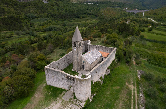 Aerial drone view of Church of the holy trinity (Cerkev Sv. Trojice) surrounded by a wall, Hrastovlje, Koper, Slovenia.