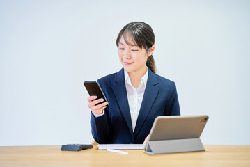 スマートフォンを操作するスーツ姿の若い女性