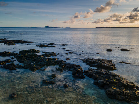 Aerial view of clear reef at sunrise with Gunner's Quoin island in the background, Pointe aux Canonniers coastline, Grand Baie, Mauritius.