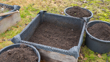Emptied out raised bed in garden in preparation of filing it with horse manure with buckets of soil around it