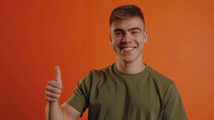 Fototapeta premium young man with dark hair and a green t-shirt. He is smiling broadly and giving a thumbs-up sign with his right hand.