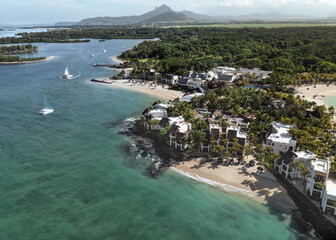 Aerial drone view of 5 star resort Shangri - La Le Touessrok with sandy beach, white villas, sailing boats and mountain range in the background, Ilot Lievres, Flacq, Mauritius.