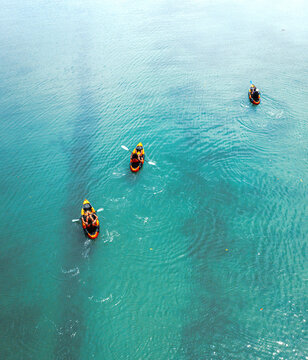 Aerial drone view of three people canoeing in orange - black canoes in the Indian Ocean, Ilot Lievres, Flacq, Mauritius.